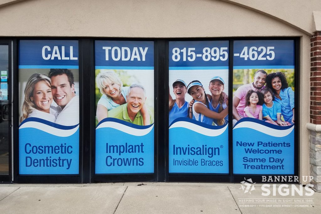 Colorful, advertising graphics cover a set of four windows on a business front.