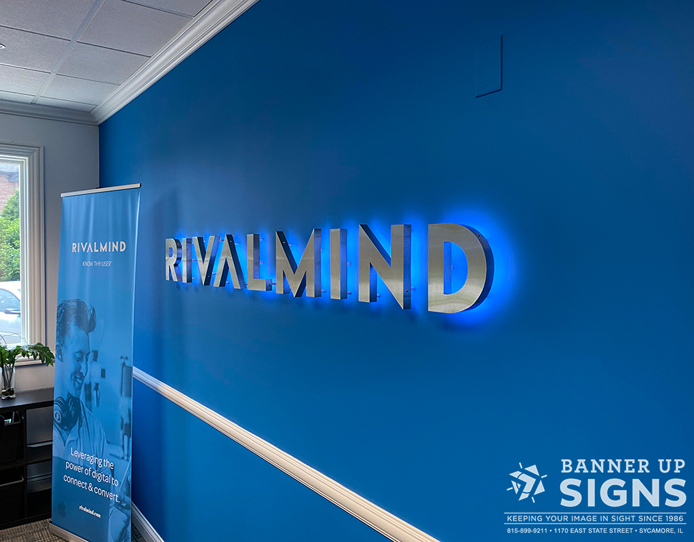Brushed aluminum letters created in the shape of a company's font held off the wall to allow blue halo lighting to illuminate around the letters.