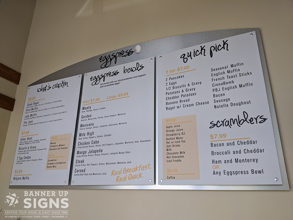 Large brushed aluminum backer hangs on the wall with 3 menu panels held in place by stand offs listing a company's food.