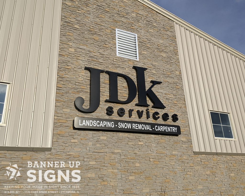 JDK Services custom dimensional logo, illuminated at night.