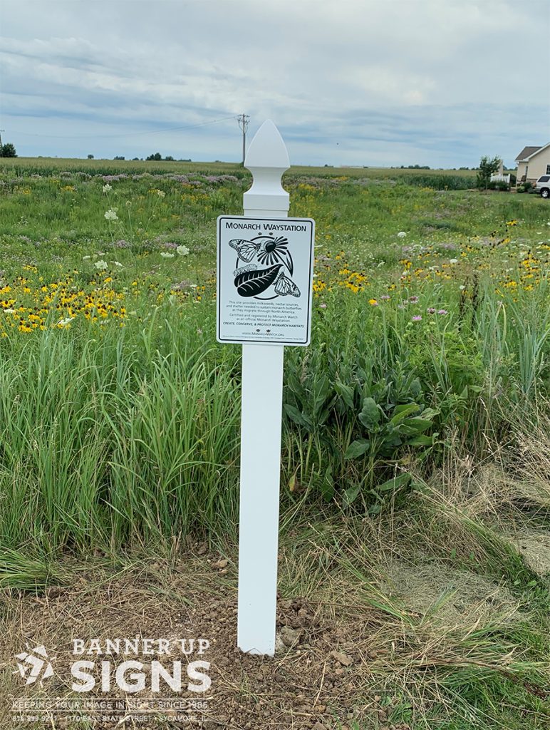 An aluminum sign on a post notes the Monarch habitat pasture in a subdivision.