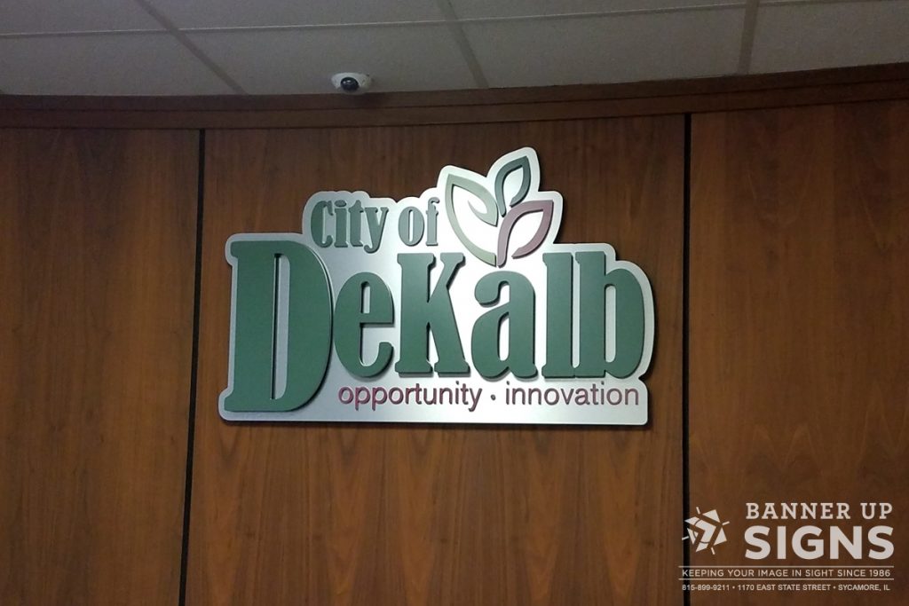 The logo for the City of DeKalb is cut out of acrylic and mounted to a brushed aluminum backer.
