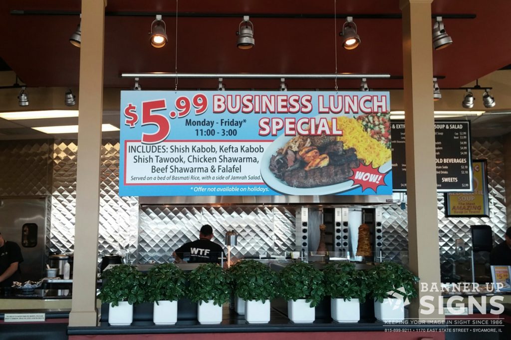A sign advertising a restaurant's lunch special hangs from a bar below channel lighting.